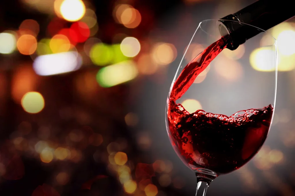 Bottle of red wine being poured into a wine glass.